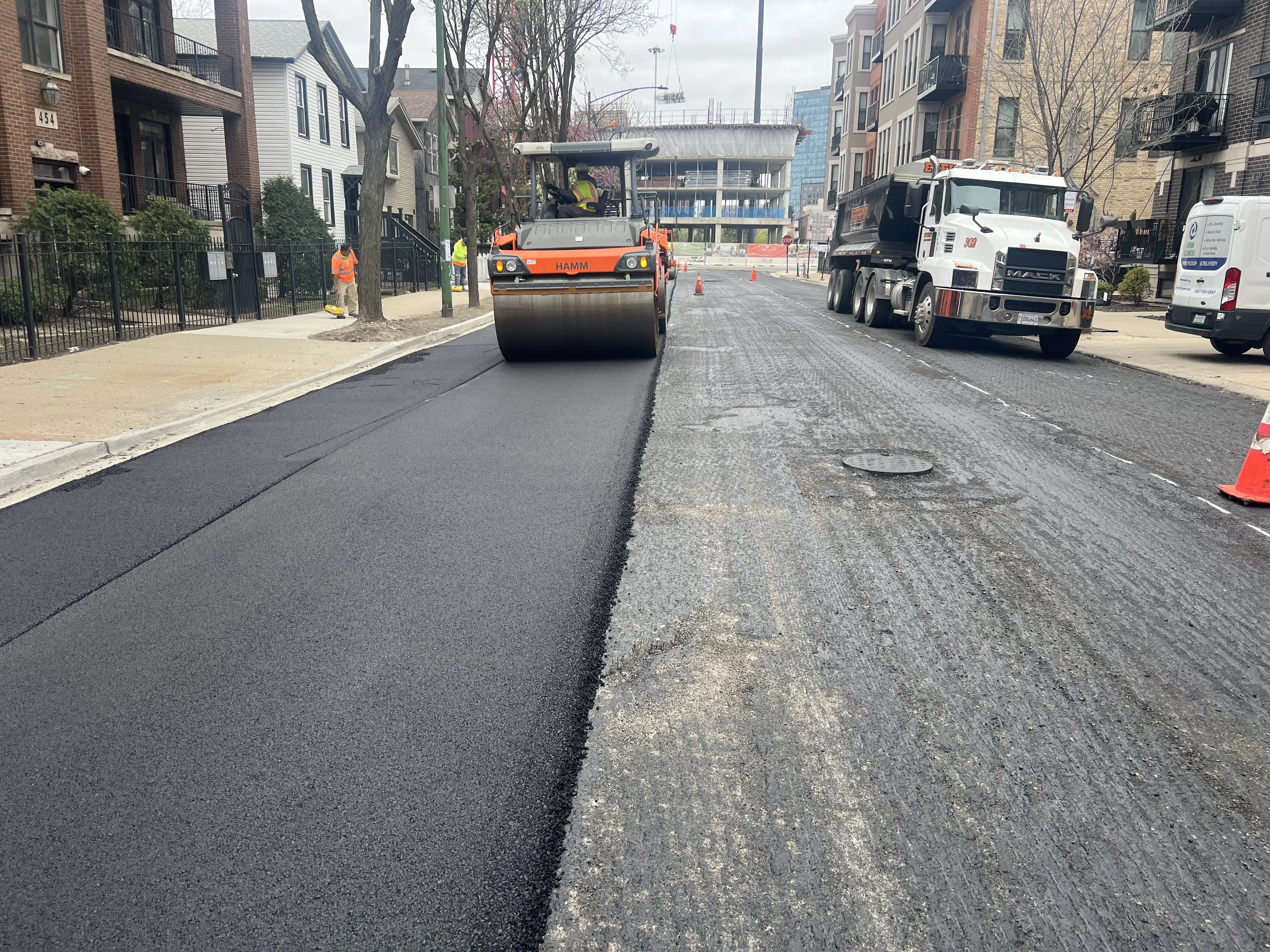A compactor passes over fresh asphalt on a residential street in Chicago.